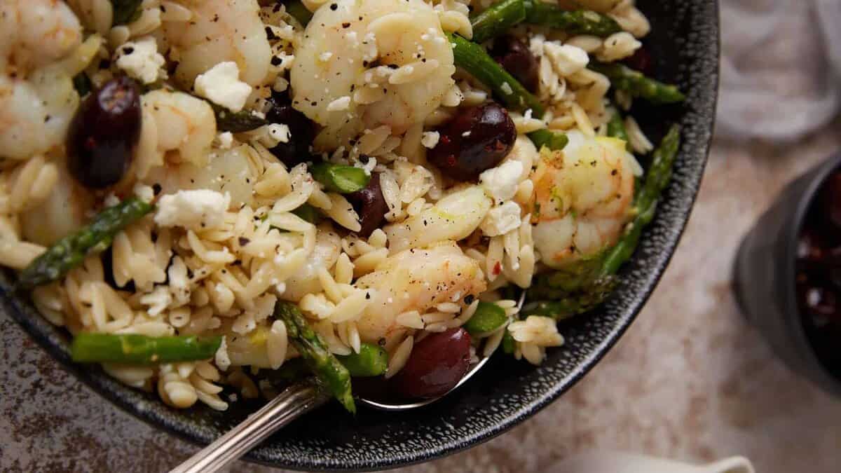 Shrimp and orzo salad with a serving spoon in a bowl.