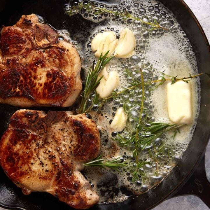 A cast iron skillet with two pork chops.