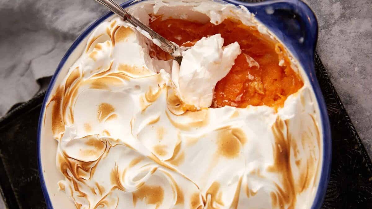 A spoon full of marshmallow topped sweet potato casserole.
