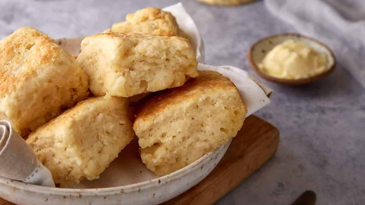 A bowl of 7 UP biscuits next to a dish of butter.