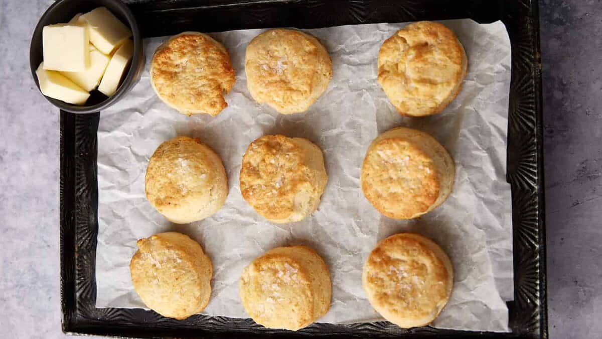 Air fryer biscuits next to a bowl of butter slices.