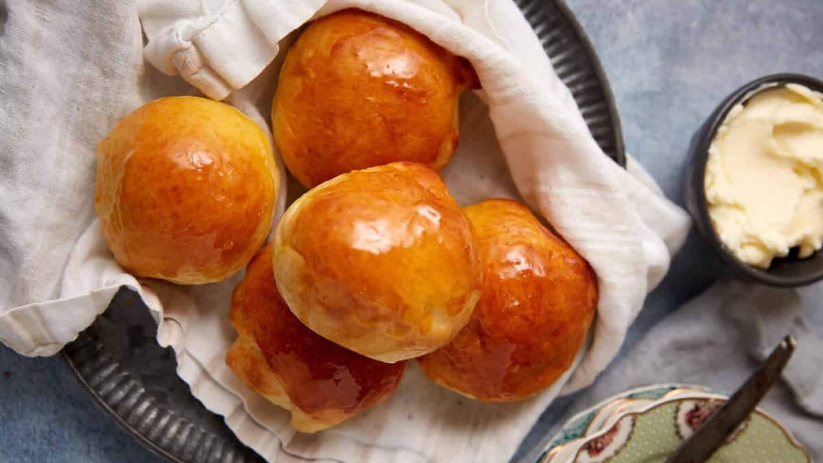 buttermilk yeast rolls on top of a towel on a plate.