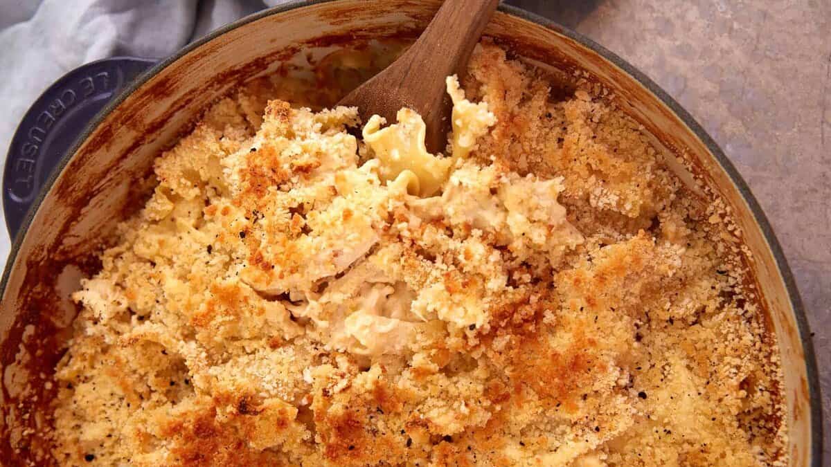 A serving spoon in a skillet of chicken casserole.