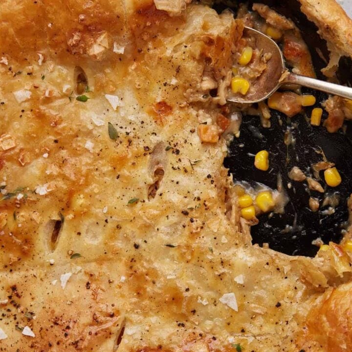A skillet of chicken pot pie covered with puff pastry.