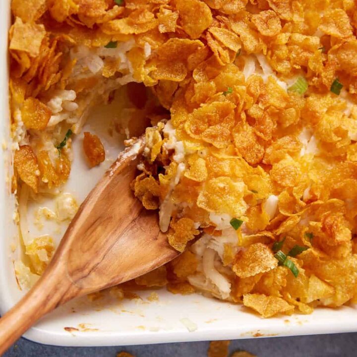 A chicken and hashbrown casserole with a wooden spoon.