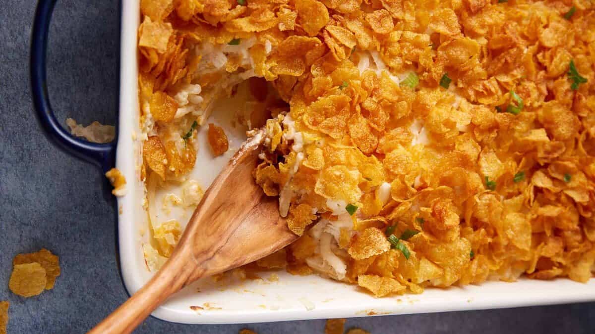 A chicken and hashbrown casserole with a wooden spoon.