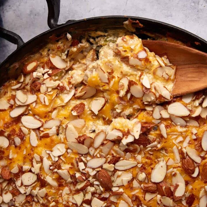A skillet of chicken and wild rice casserole with a wooden spoon.