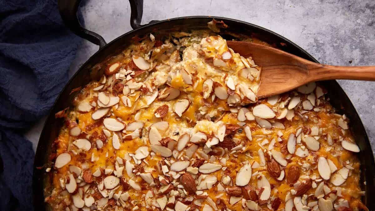 A skillet of chicken and wild rice casserole with a wooden spoon.