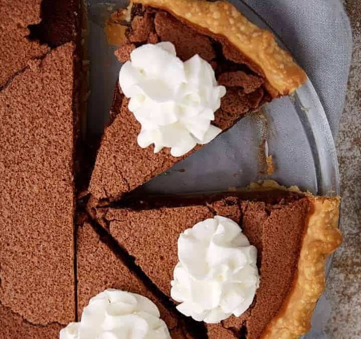 A chocolate chess pie topped with whip cream swirls.