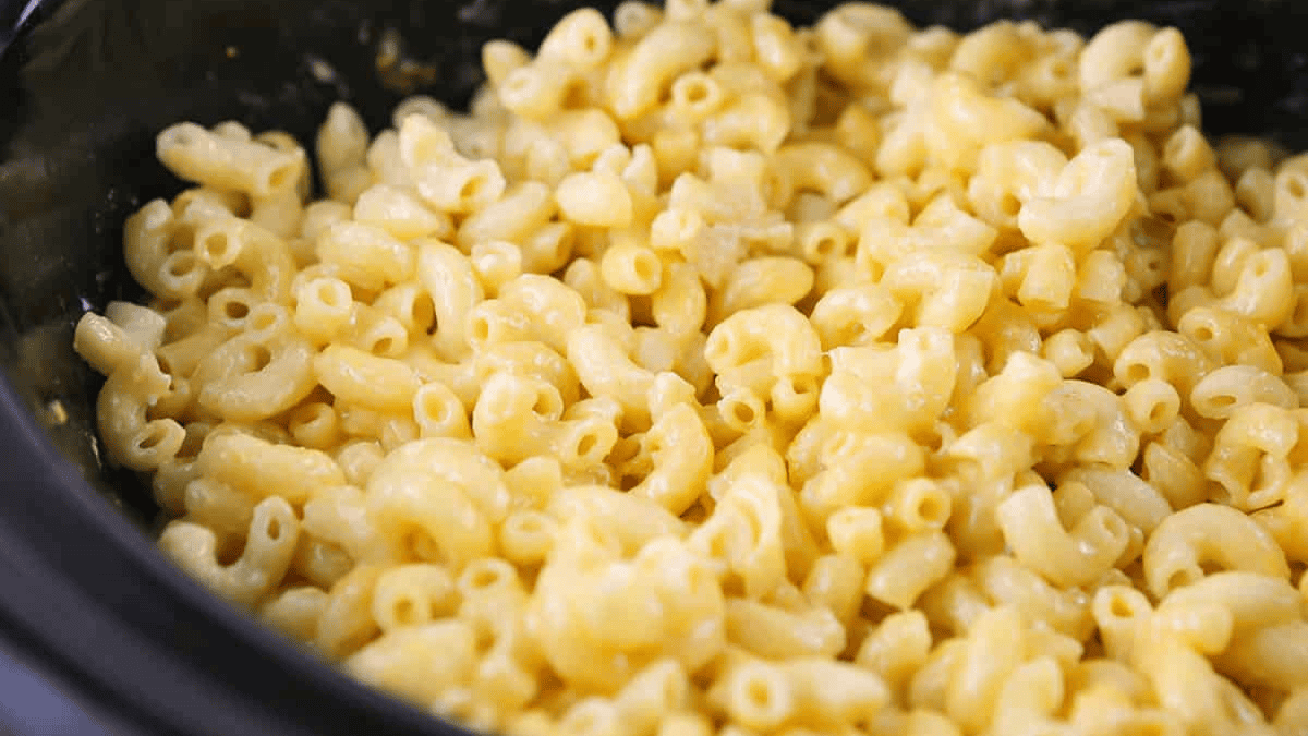 Close-up of creamy macaroni and cheese, showing elbow pasta coated in a rich, melted cheese sauce. The dish appears hot and freshly made, with a soft and smooth texture.