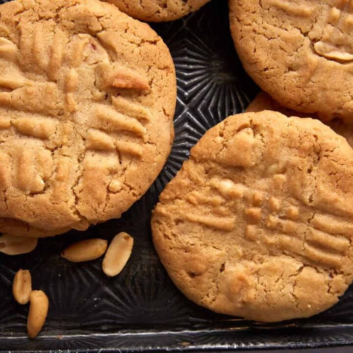 Peanut butter cookies on a tray with roasted peanuts.