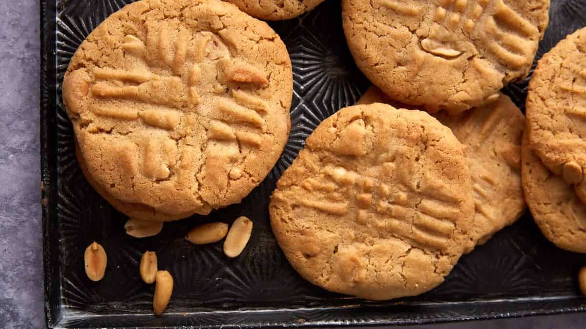 Peanut butter cookies on a tray with roasted peanuts.