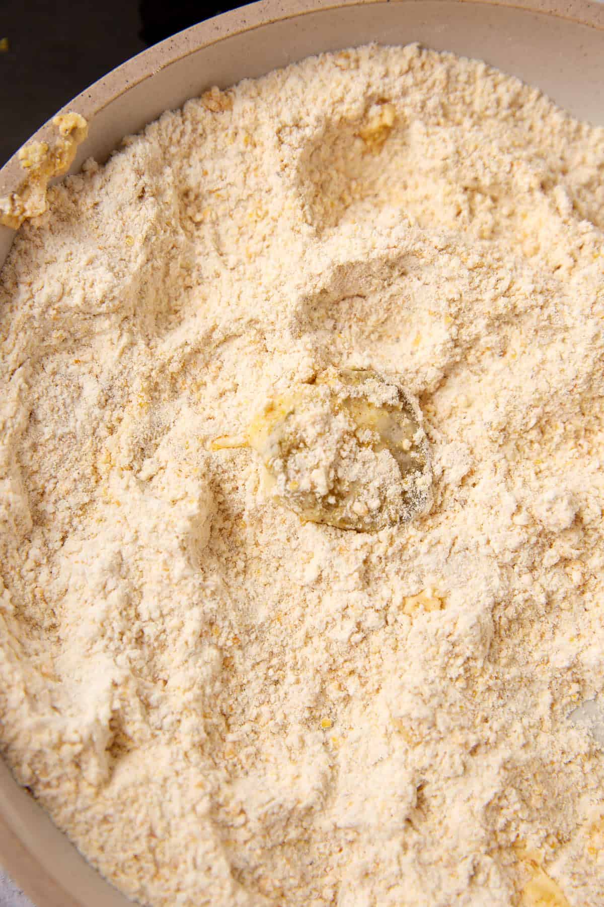 A close-up of a bowl filled with flour and small chunks of butter, showing the beginning stages of mixing dough or pastry by hand—just like prepping for classic Southern Fried Pickles.