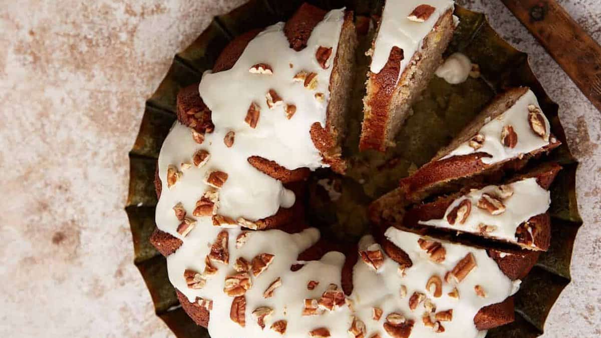 A hummingbird cake sliced next to cups of coffee.