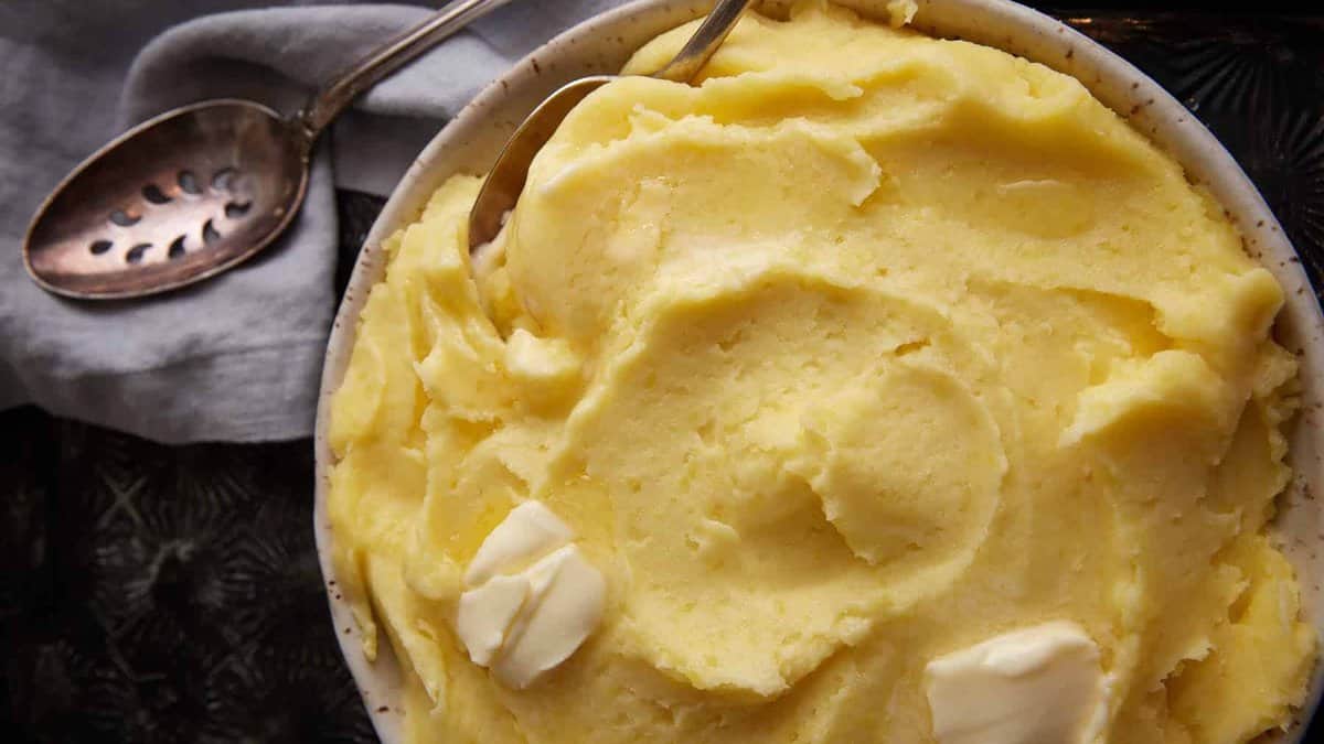 A bowl full of creamy mashed potatoes with butter melting on top.