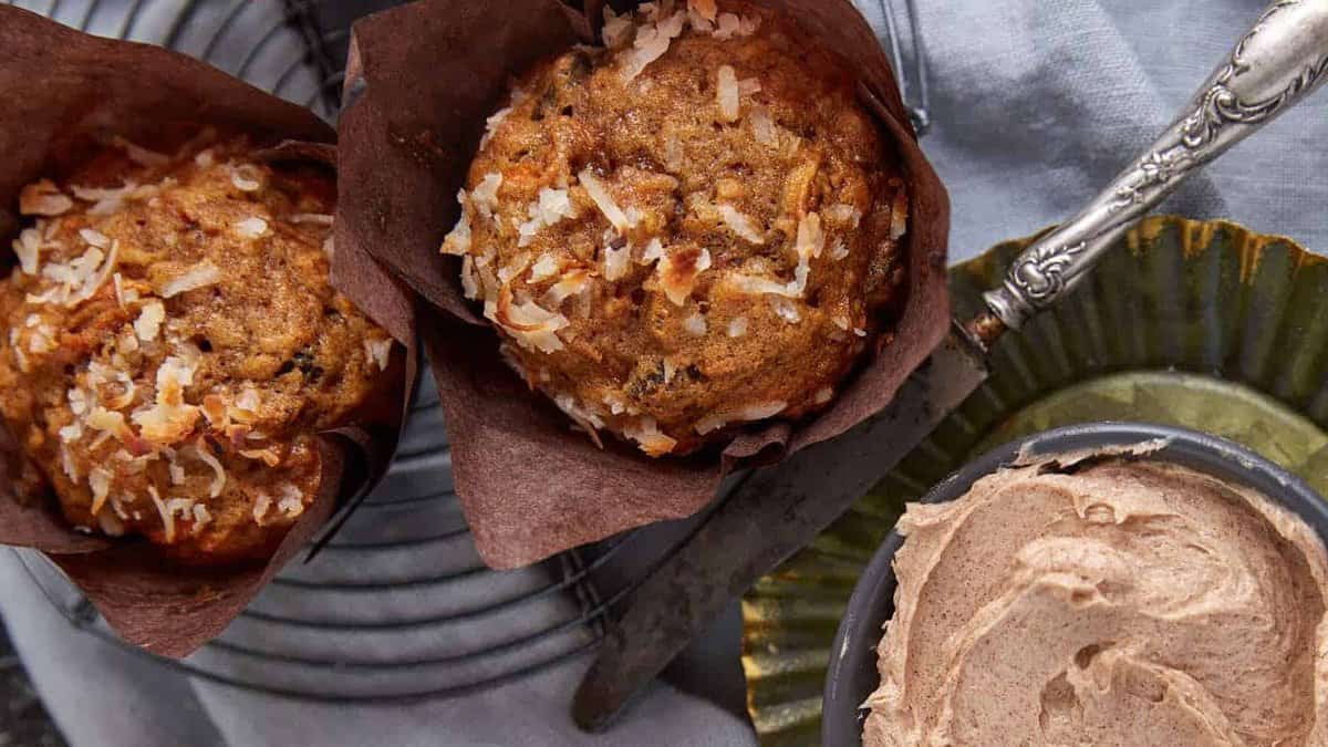Two morning glory muffins next to a bowl of cinnamon butter.