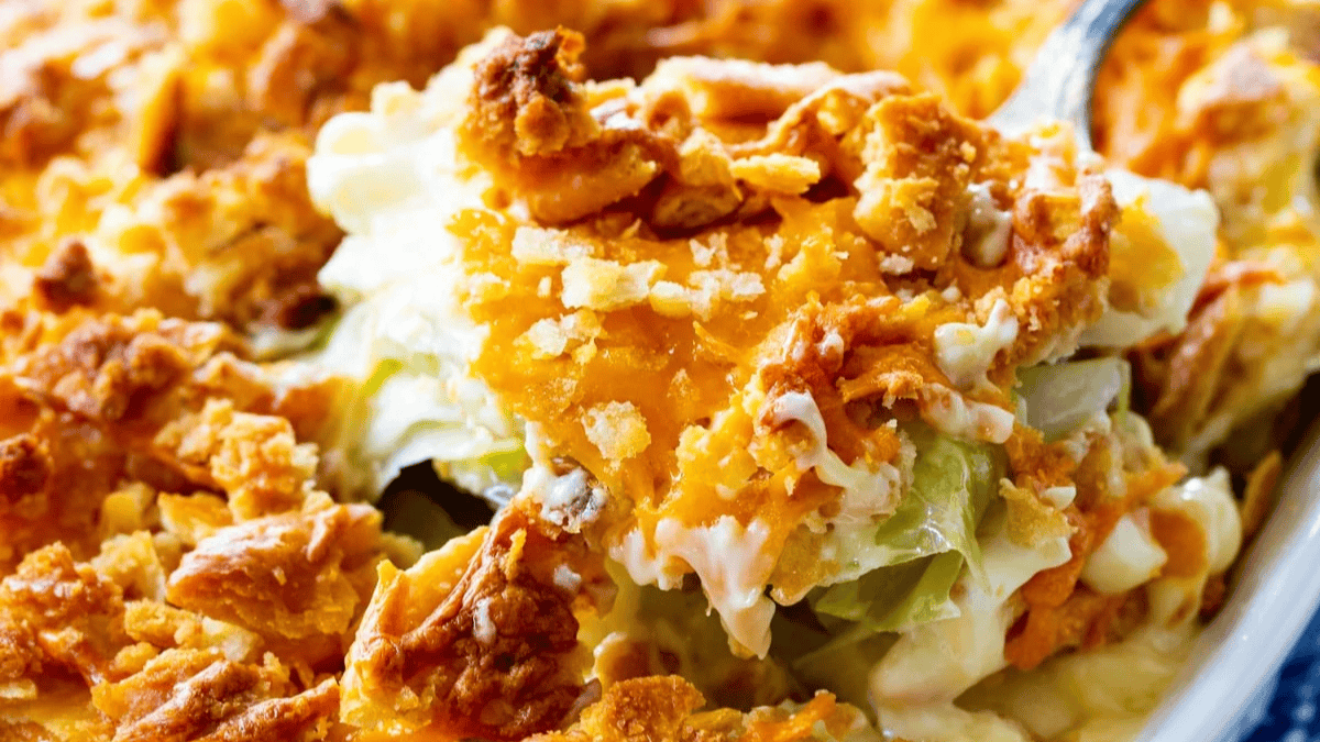 A close-up of a cheesy casserole with a golden, crispy topping and creamy filling, showing melted cheese and crunchy bits on top.