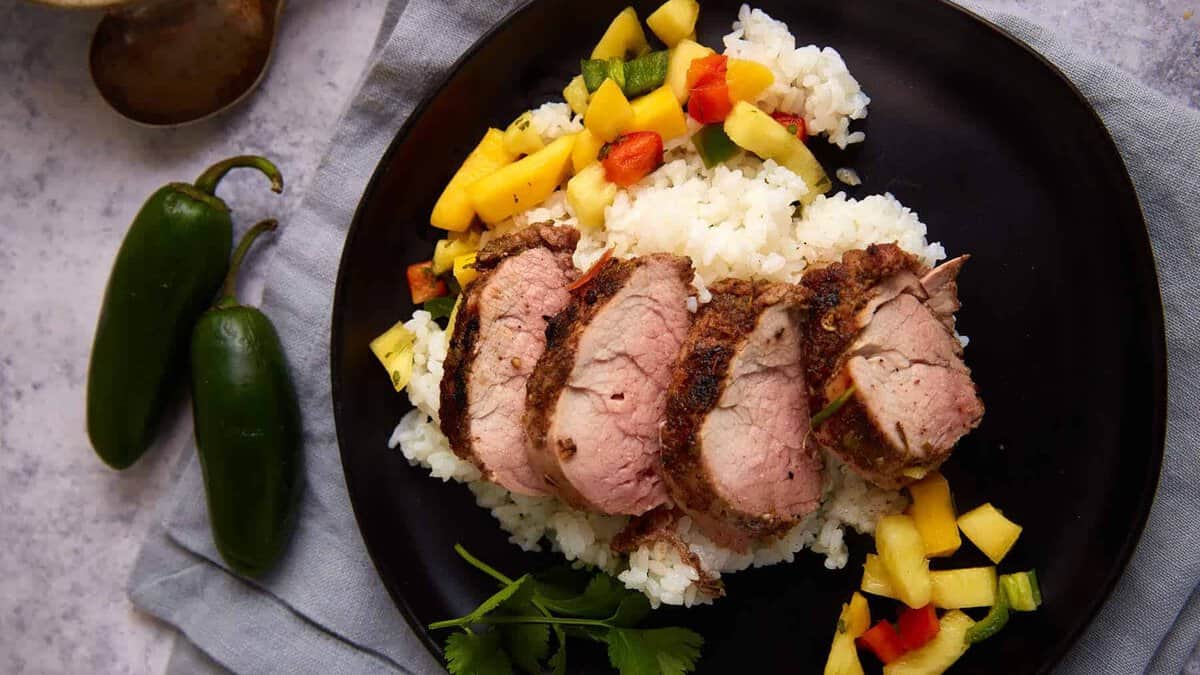 A plate of grilled pork tenderloin over rice.
