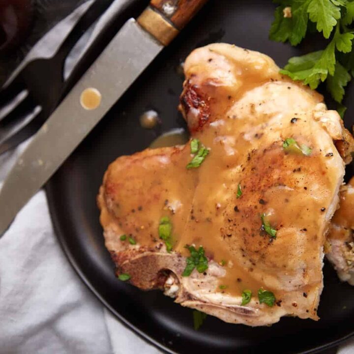 A stuffed pork chop on a plate covered in gravy.