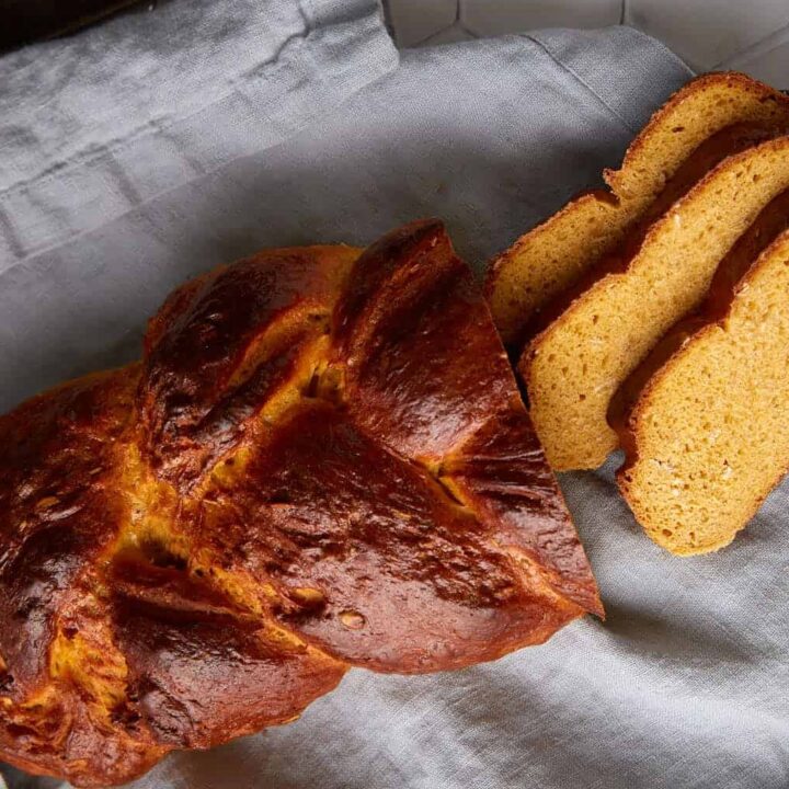 A braided loaf of bread with three slices.