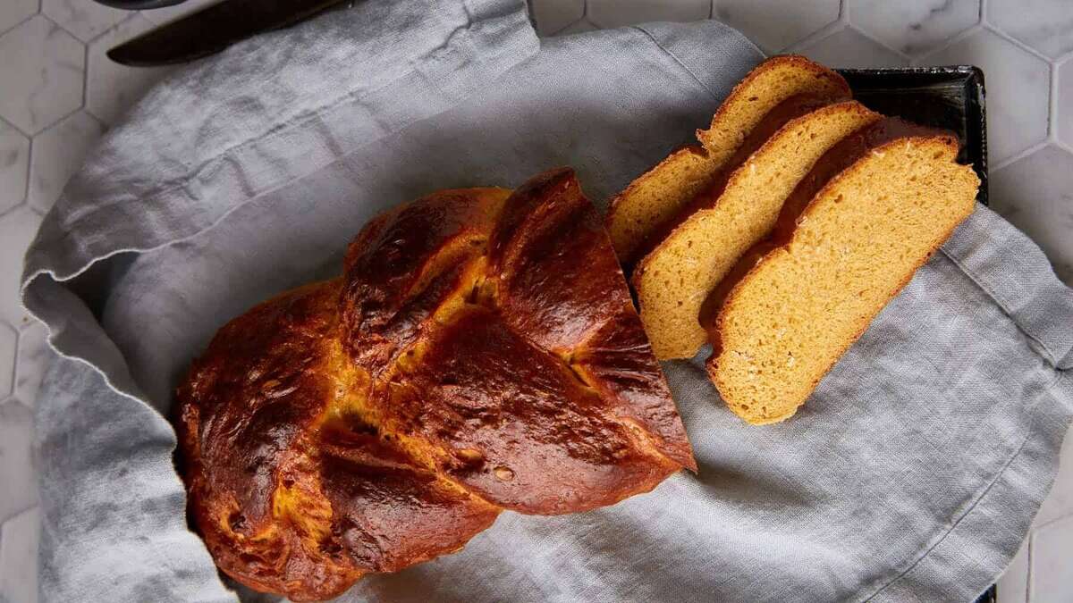 A braided loaf of bread with three slices.