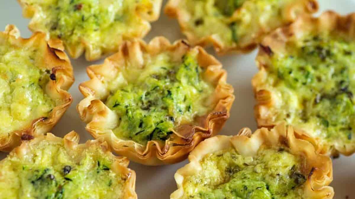 A platter of zucchini quiches with basil leaves.