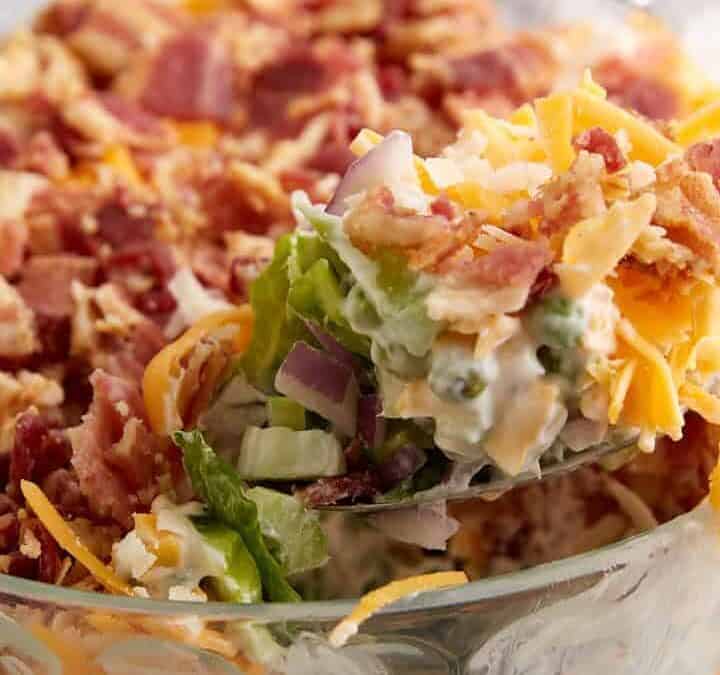 A spoon full of seven layer salad.