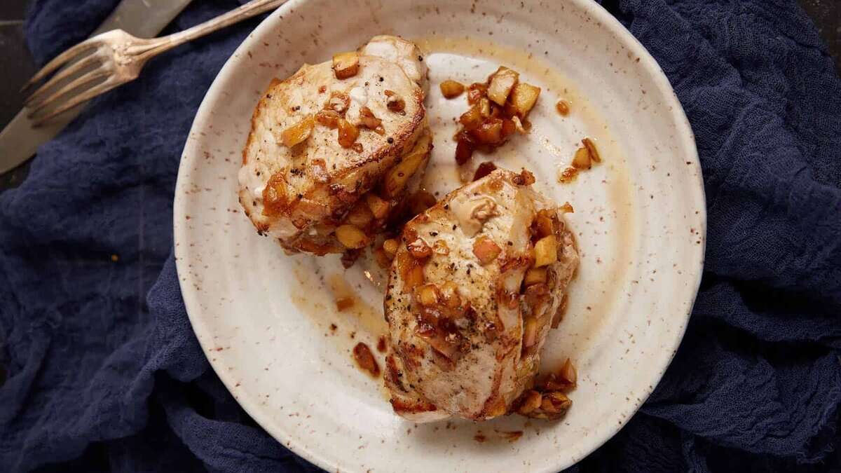 Two apple stuffed pork chops on a plate.
