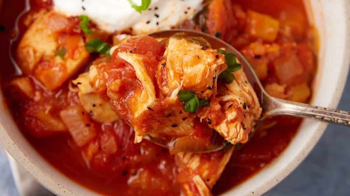 A bowl of chicken chili with sour cream on top.