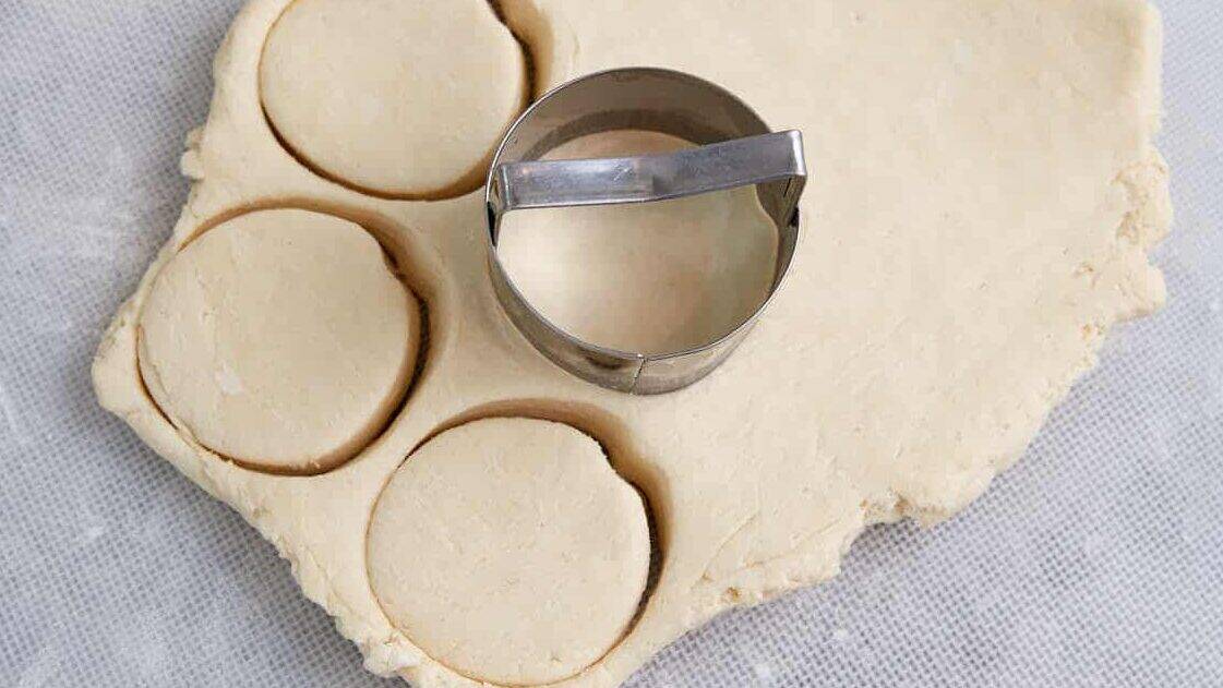 Biscuit dough with a round biscuit cutter.
