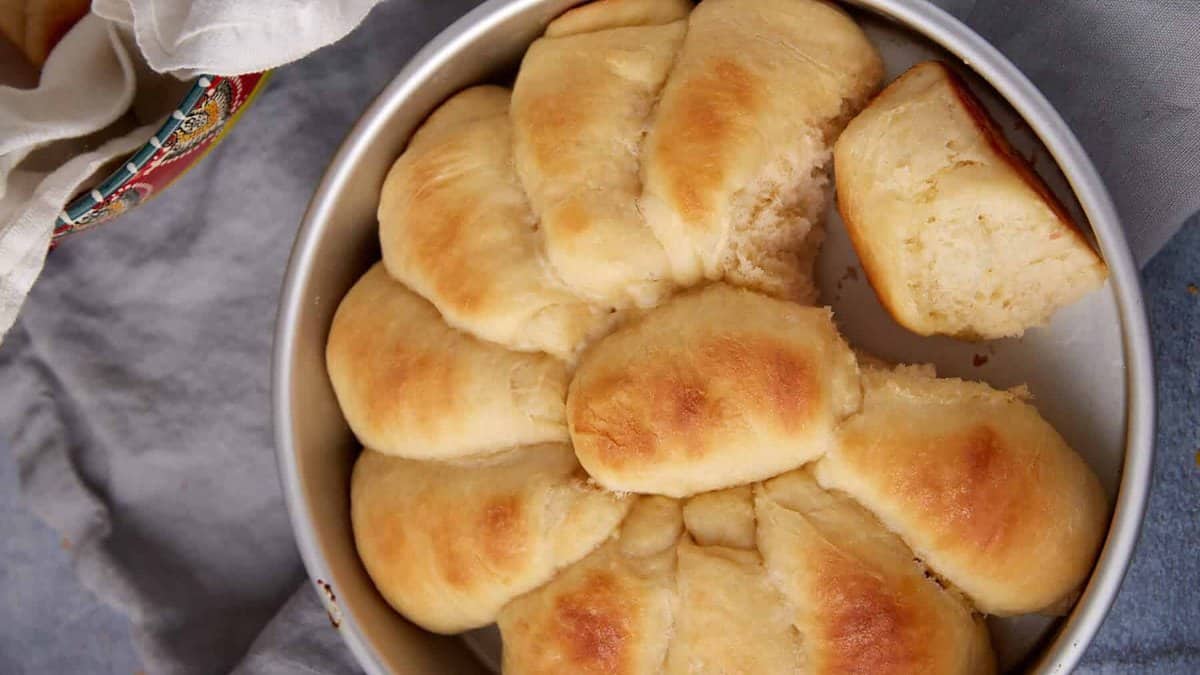 A cake pan with baked yeast rolls.