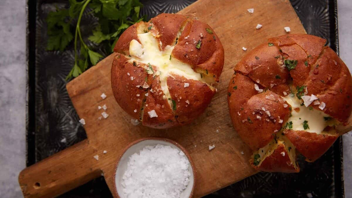 Two stuffed garlic rolls on a wooden board.