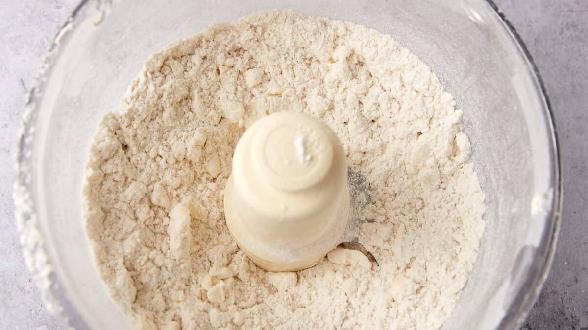 A food processor with butter incorporated into the flour mixture.