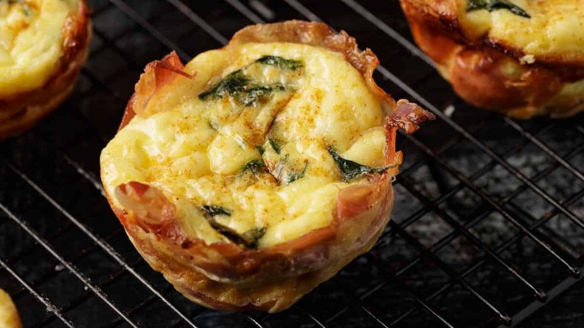 Egg cups wrapped in prosciutto on a black rack