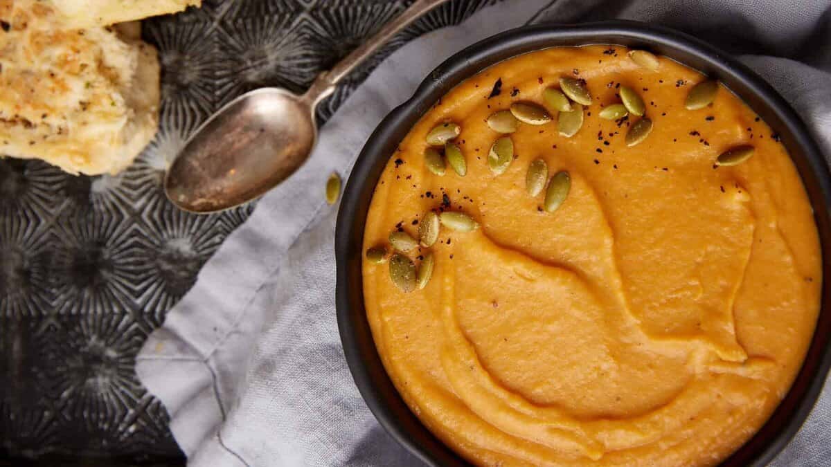 Sweet potato soup in a bowl with pumpkin seeds.