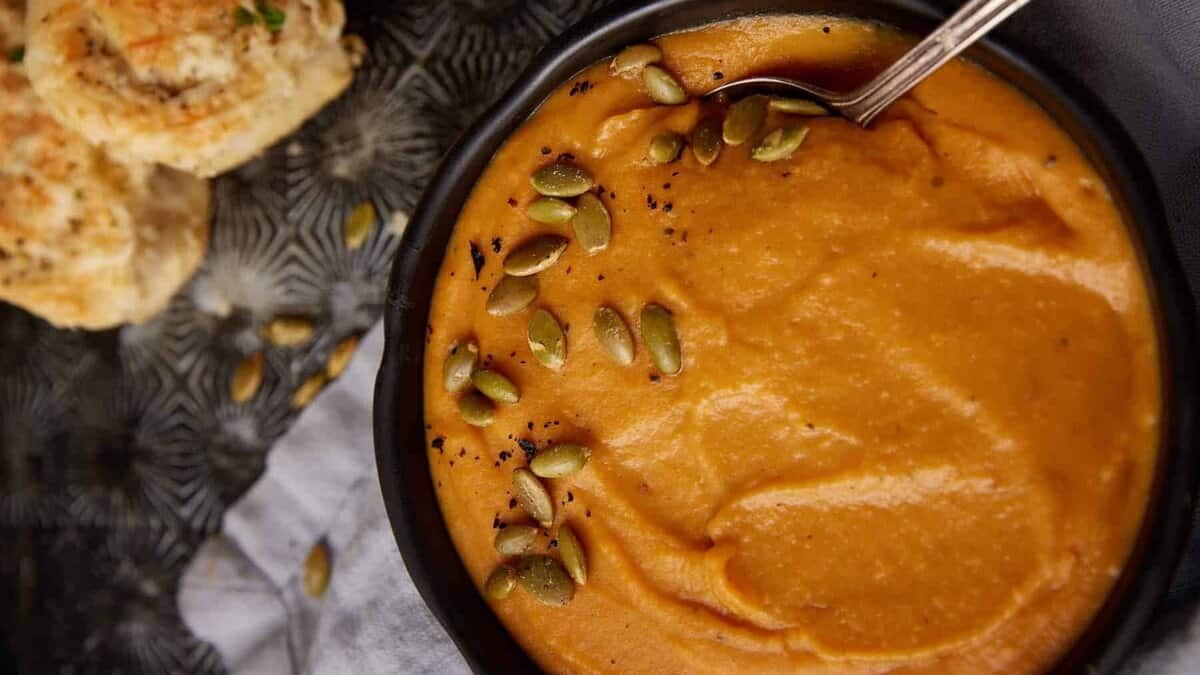 A bowl of sweet potato soup with a spoon in it.