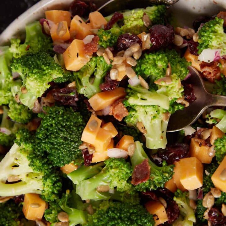 A bowl of broccoli salad with a serving spoon.