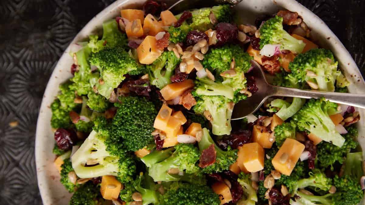 A bowl of broccoli salad with a serving spoon.