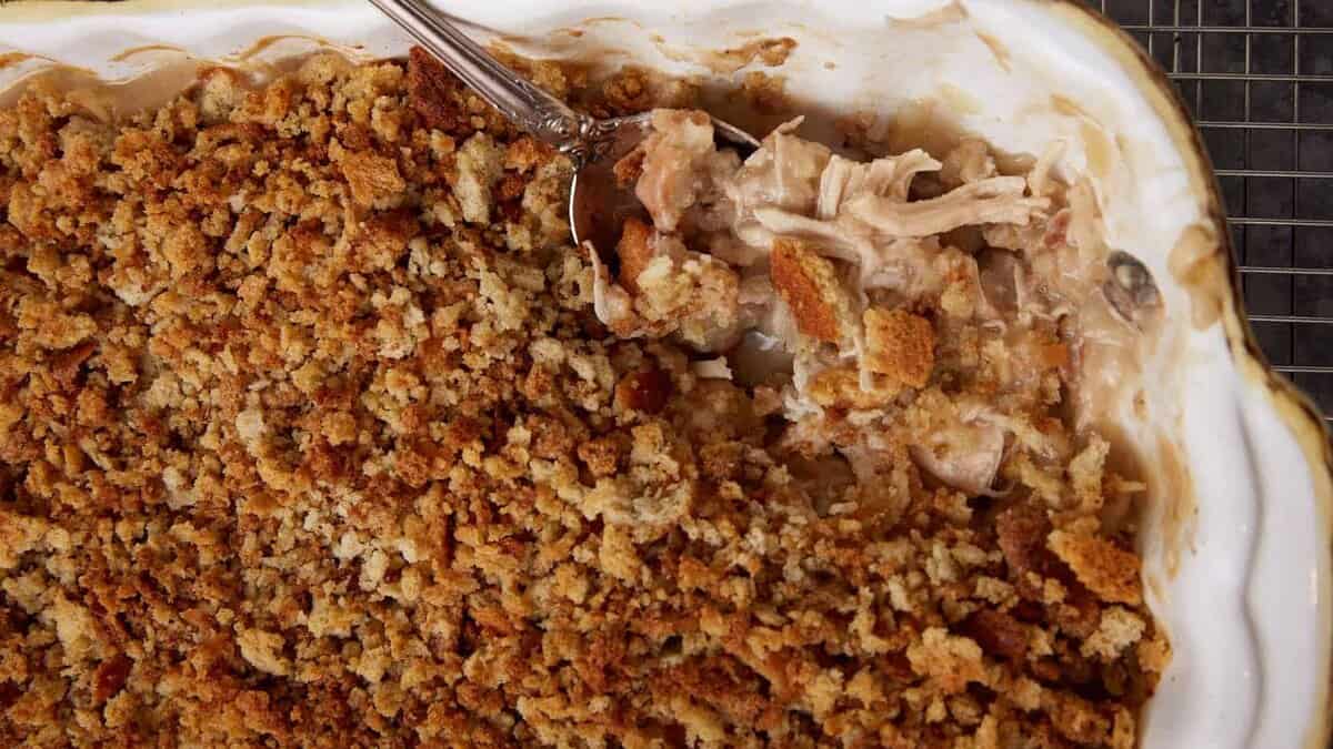 A serving spoon in a baking dish of chicken stuffing casserole.