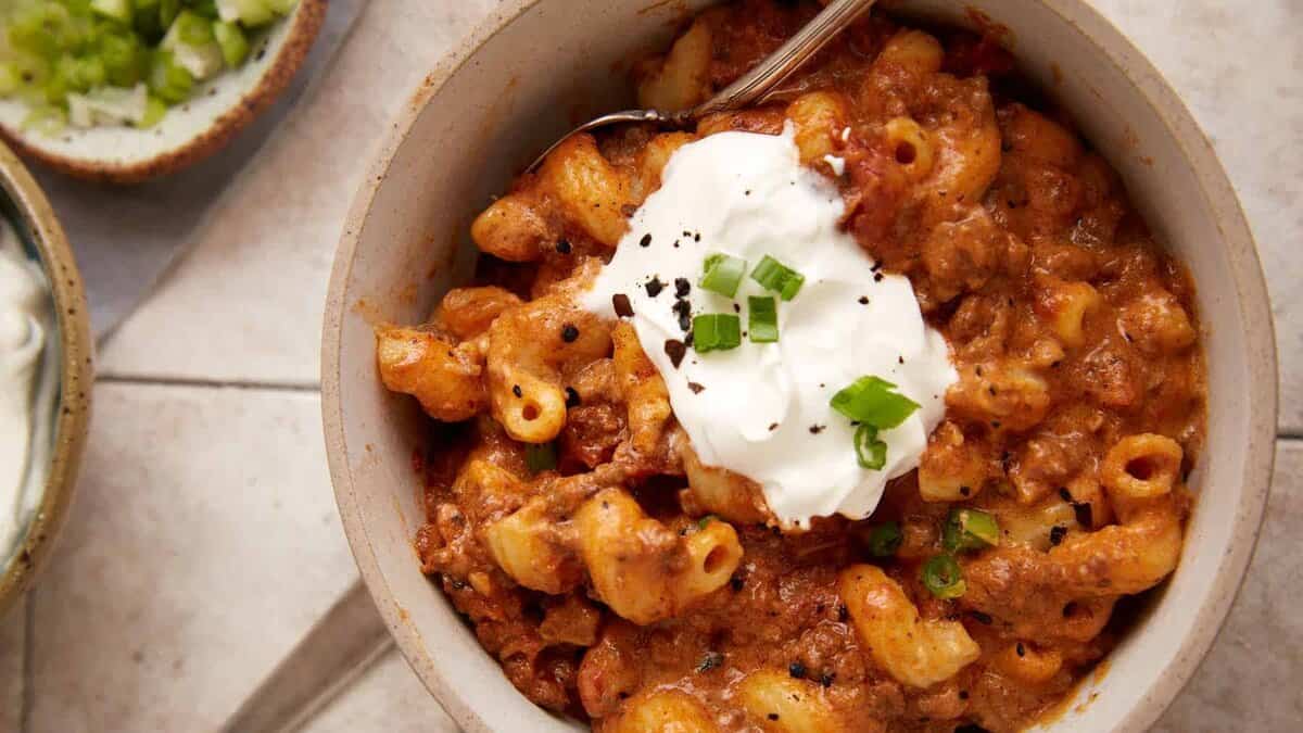 A bowl of chili mac topped with sour cream.