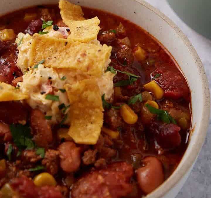 Bowls of crock pot taco soup next to graded cheese and sour cream.
