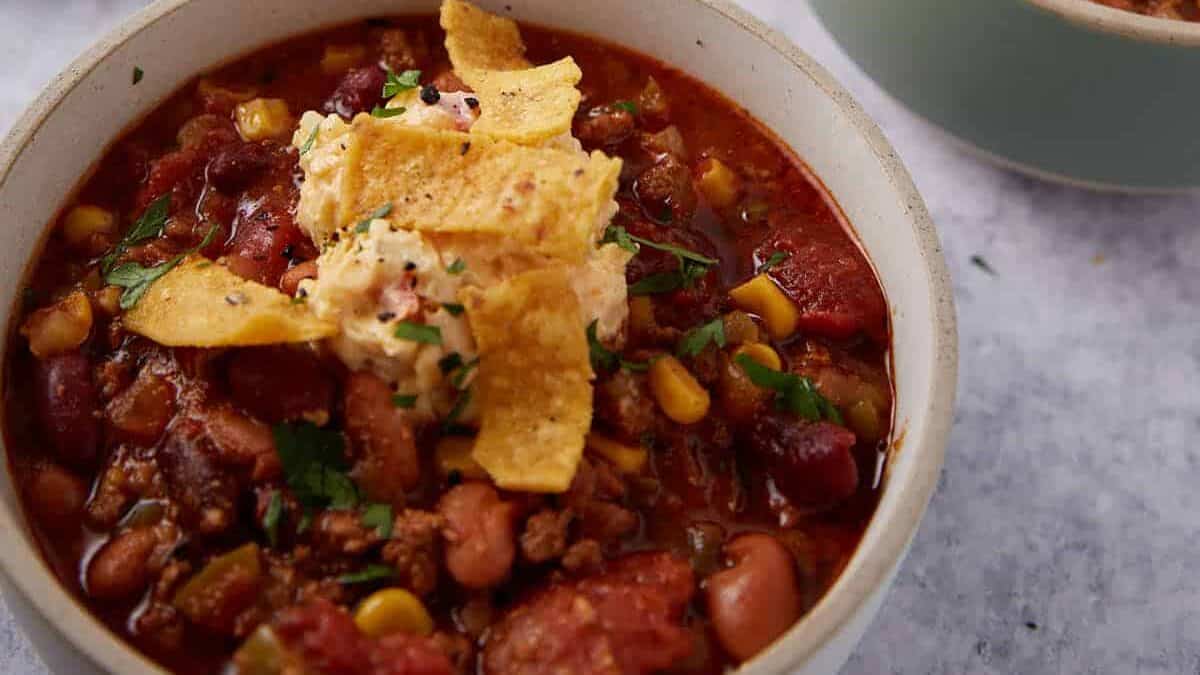 Bowls of crock pot taco soup next to graded cheese and sour cream.