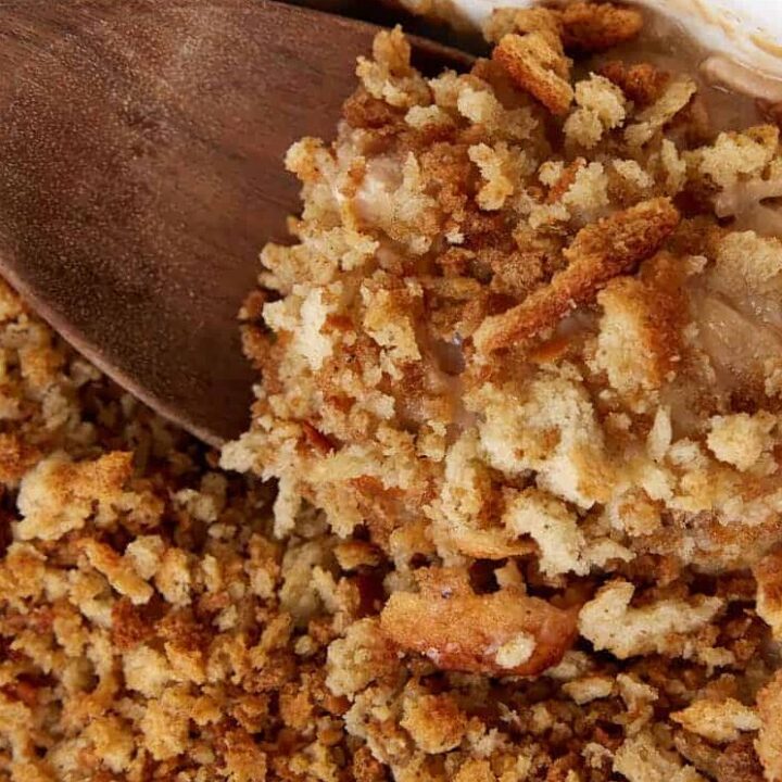 A wooden spoon dipping out a serving of chicken and stuffing.