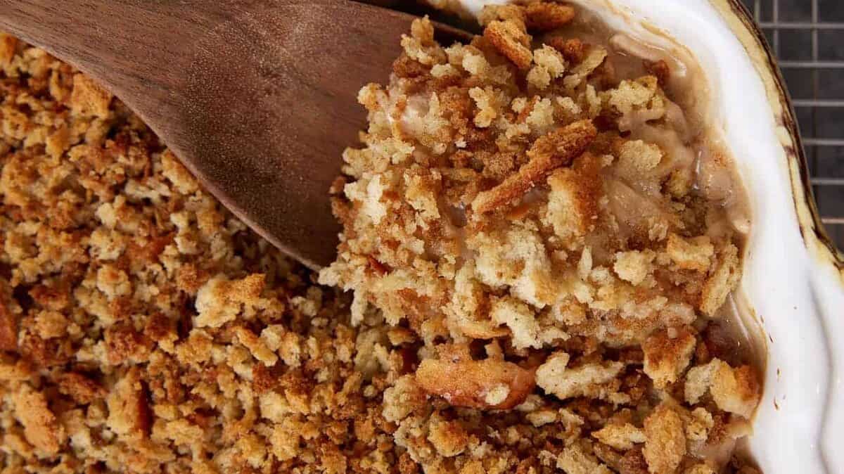A wooden spoon dipping out a serving of chicken and stuffing.