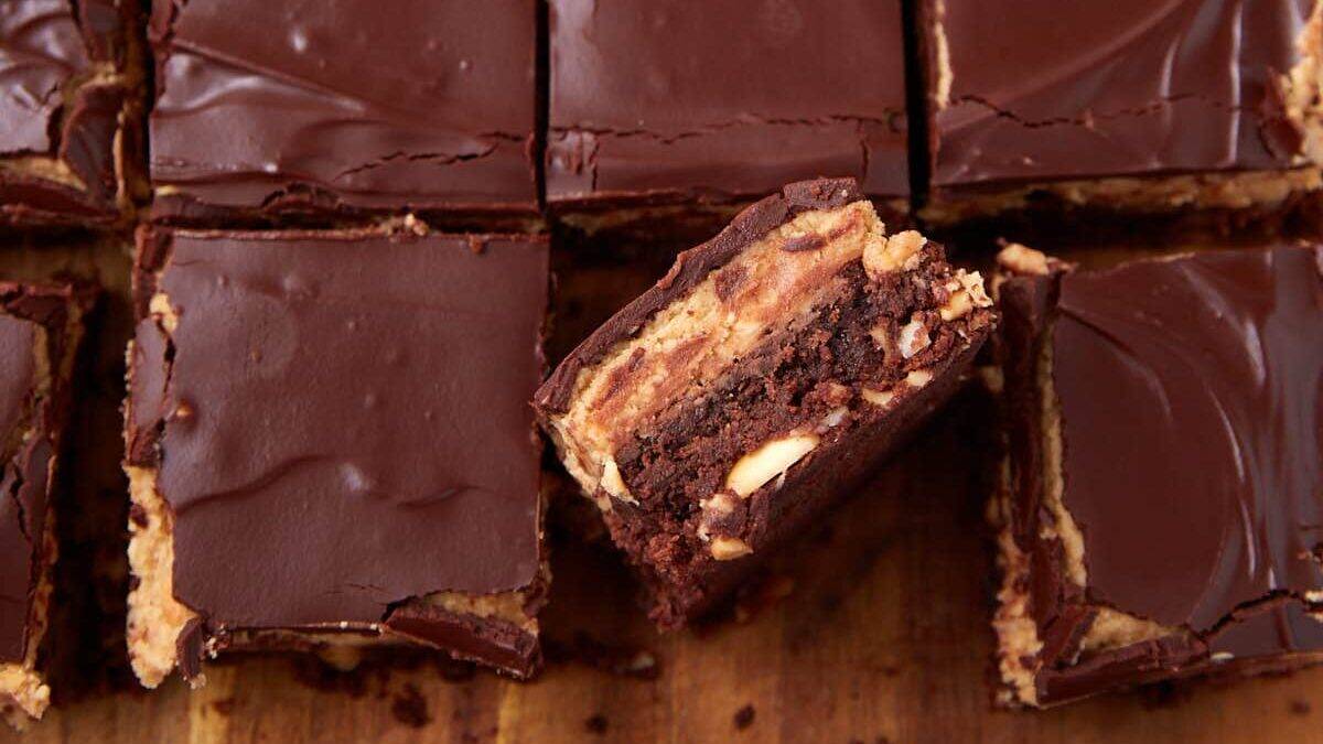 Close-up of chocolate peanut butter bars cut into squares. One bar is turned on its side, showing chocolate, peanut butter, and peanuts—holiday dessert bars that beat cookies for both flavor and festive flair.