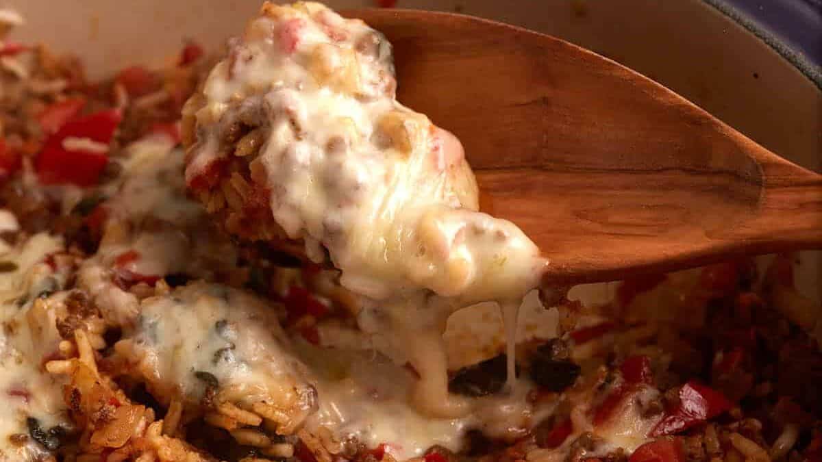 A wooden spoon with a scoop of hamburger rice casserole.