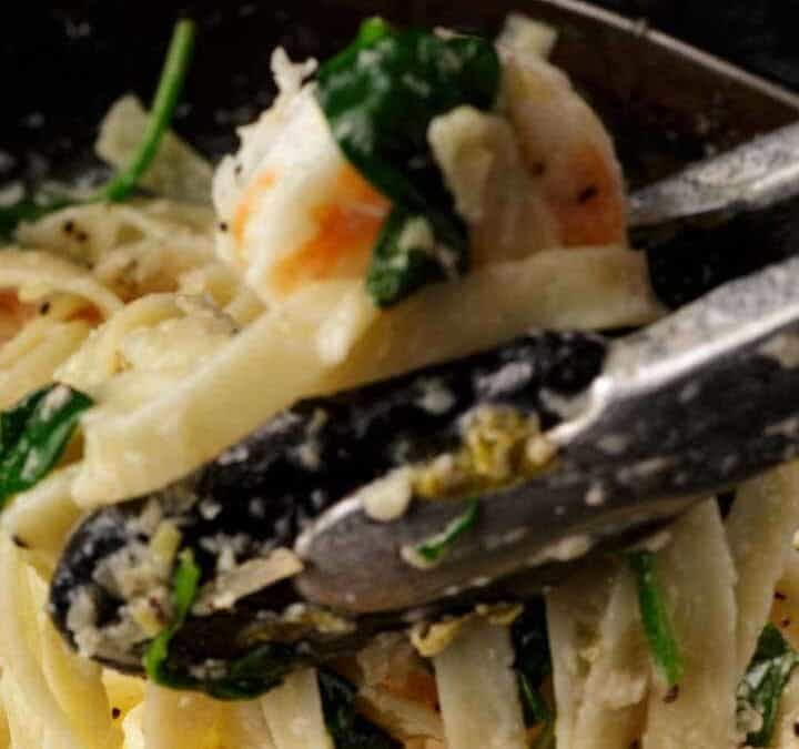 Pasta being remove from a skillet.
