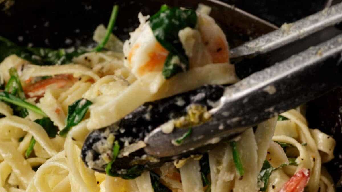 Pasta being remove from a skillet.
