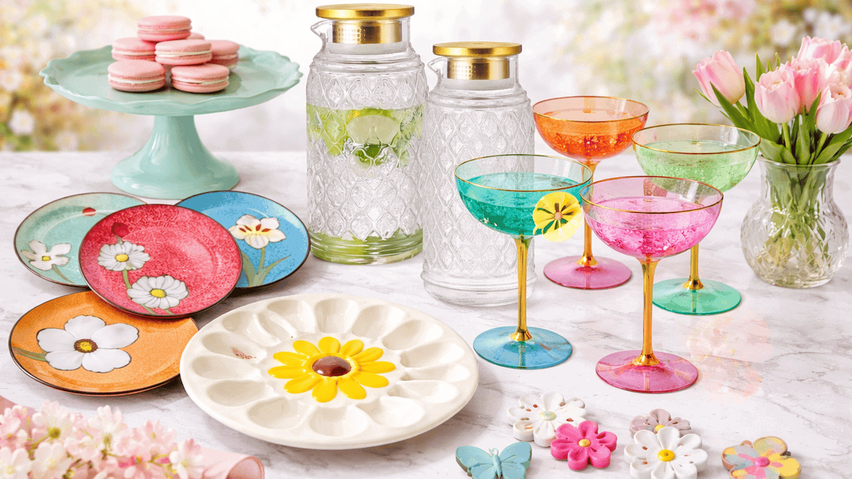 A spring-themed table setting with colorful flower plates, pastel macarons, two glass pitchers with gold lids, bright cocktail glasses, floral coasters, and pink tulips—make Easter easy with these brunch recipes for a festive touch.